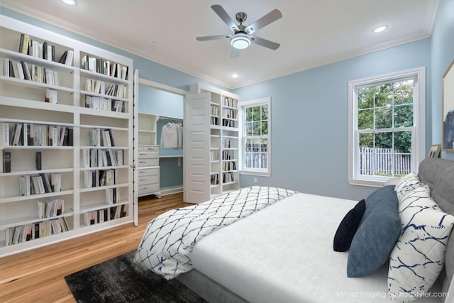 bedroom featuring ceiling fan, wood-type flooring, crown molding, and a closet