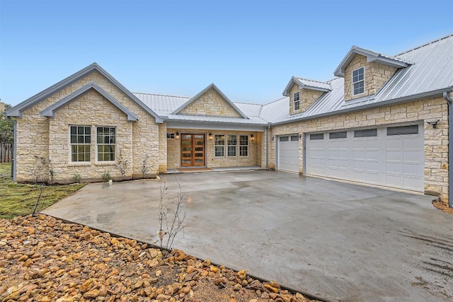 205 Vitex Dr, Lakeway, TX 78734 - view of front of home with stone siding, french doors, driveway, a garage, and metal roof