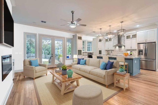 205 Vitex Dr, Lakeway, TX 78734 - living room with light wood-style flooring, french doors, ceiling fan, baseboards, and crown molding