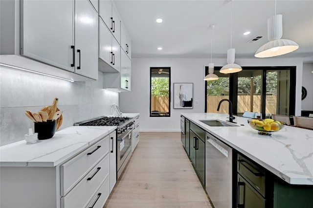 kitchen featuring sink, white cabinetry, stainless steel appliances, and hanging light fixtures