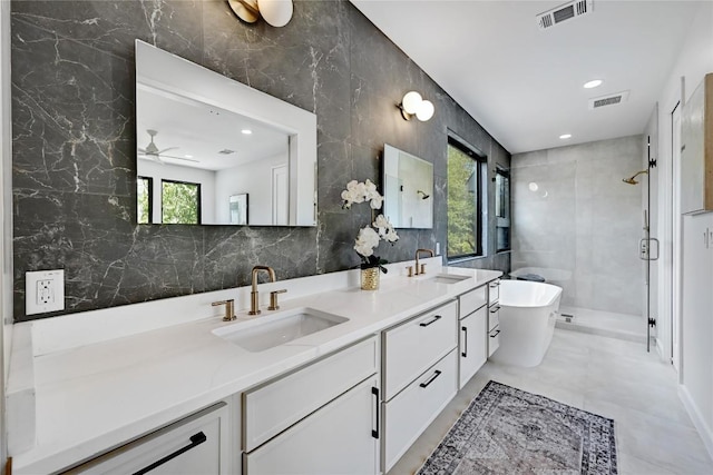 bathroom with shower with separate bathtub, vanity, ceiling fan, and tile walls