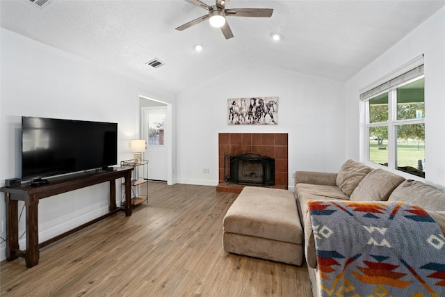 living room with ceiling fan, wood-type flooring, a textured ceiling, vaulted ceiling, and a fireplace