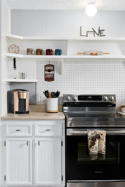 kitchen featuring white cabinets, a textured ceiling, and stainless steel electric range