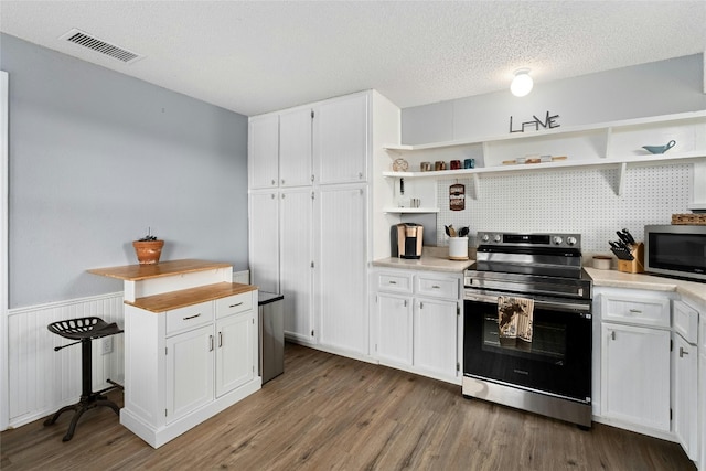 kitchen with a textured ceiling, white cabinets, stainless steel appliances, and dark hardwood / wood-style floors