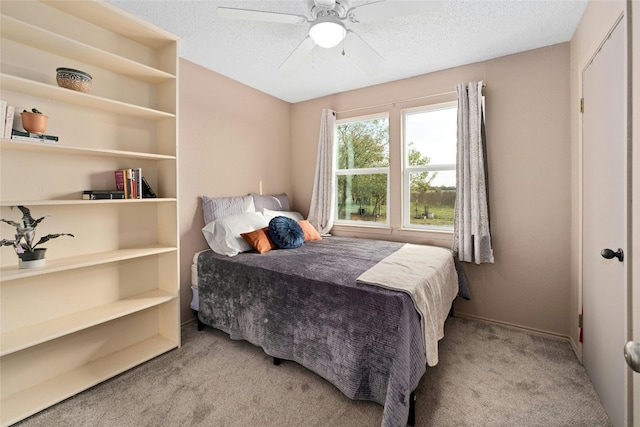 carpeted bedroom featuring ceiling fan and a textured ceiling