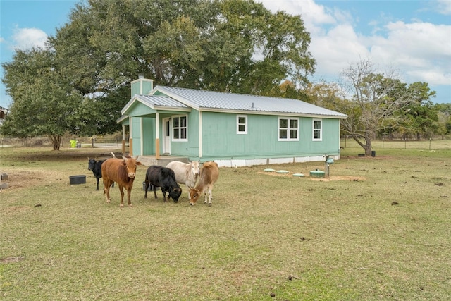 back of house featuring a yard and a rural view