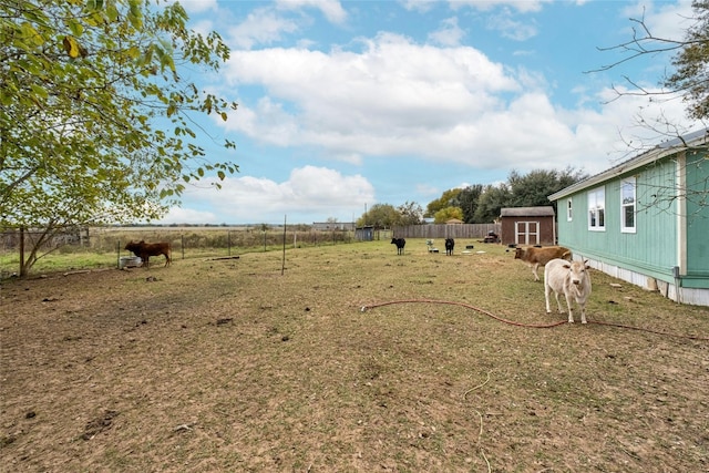 view of yard featuring a rural view and a storage shed