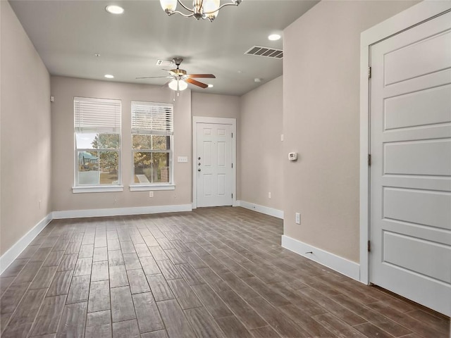 spare room with dark hardwood / wood-style flooring and ceiling fan with notable chandelier