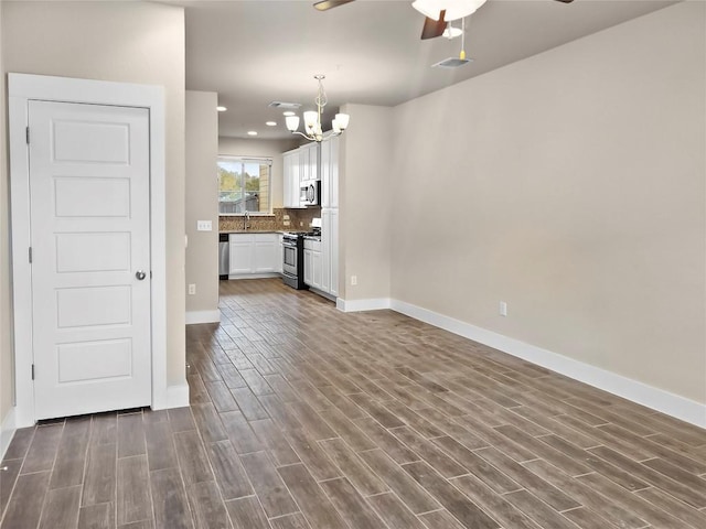 unfurnished living room with ceiling fan with notable chandelier, dark hardwood / wood-style floors, and sink