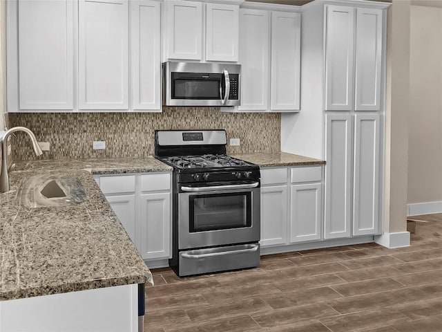 kitchen with dark hardwood / wood-style floors, white cabinetry, appliances with stainless steel finishes, and tasteful backsplash