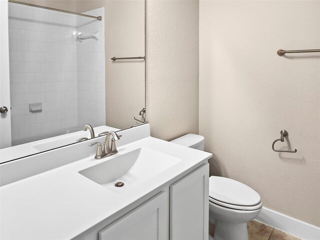 bathroom featuring toilet, a tile shower, vanity, and tile patterned floors