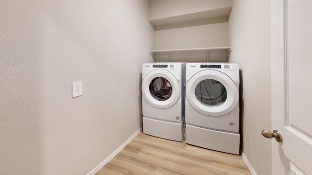 clothes washing area featuring separate washer and dryer and light hardwood / wood-style flooring