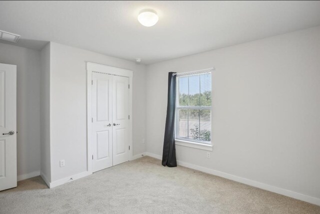 unfurnished bedroom featuring light carpet and a closet