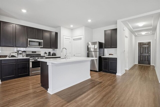 kitchen featuring a kitchen island with sink, sink, dark hardwood / wood-style floors, decorative backsplash, and stainless steel appliances