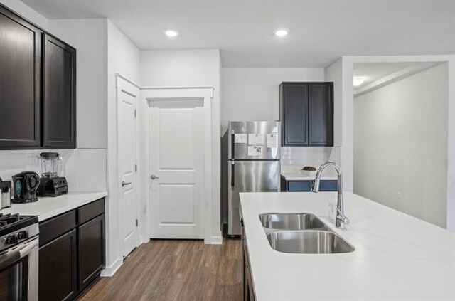 kitchen featuring dark brown cabinetry, sink, tasteful backsplash, dark hardwood / wood-style floors, and appliances with stainless steel finishes