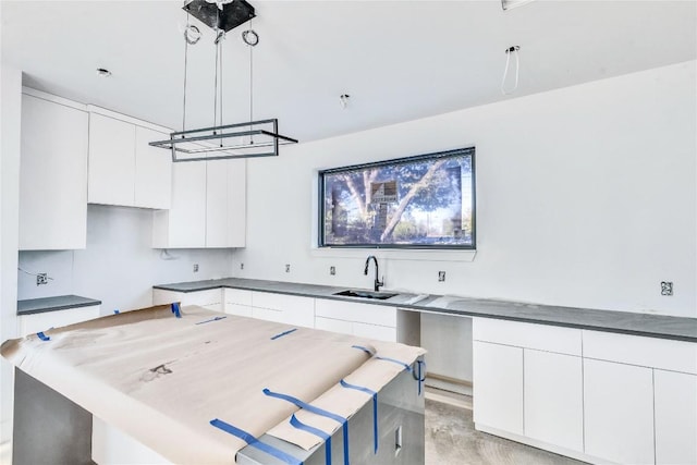 kitchen with white cabinetry, sink, and decorative light fixtures