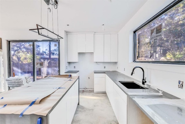 kitchen featuring decorative light fixtures, a healthy amount of sunlight, white cabinetry, and sink