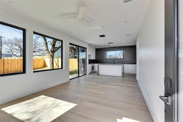 interior space with a ceiling fan, baseboards, light wood-type flooring, and a sink