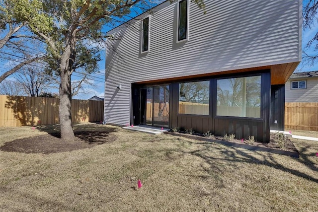 rear view of house with a lawn and fence