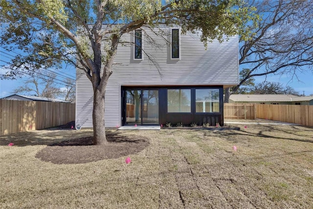 rear view of property with a yard and a fenced backyard