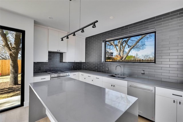 kitchen with backsplash, white cabinetry, stainless steel appliances, and a sink