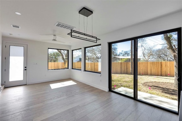 unfurnished sunroom with visible vents and a ceiling fan