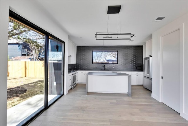 kitchen with backsplash, visible vents, high quality appliances, and white cabinetry