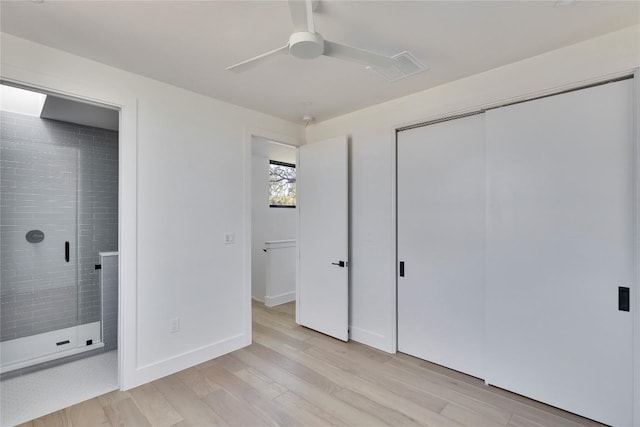 unfurnished bedroom featuring connected bathroom, baseboards, ceiling fan, light wood-style floors, and a closet