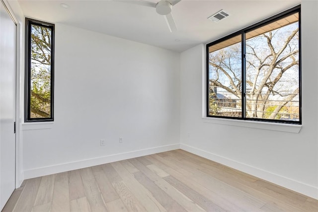 spare room featuring baseboards, visible vents, a wealth of natural light, and light wood-type flooring