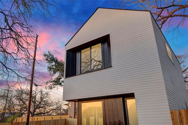 property exterior at dusk featuring fence