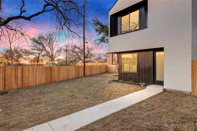 yard at dusk with a fenced backyard