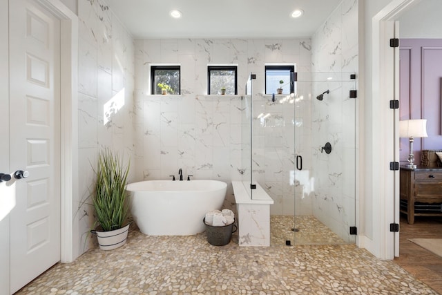 bathroom featuring tile walls and plus walk in shower