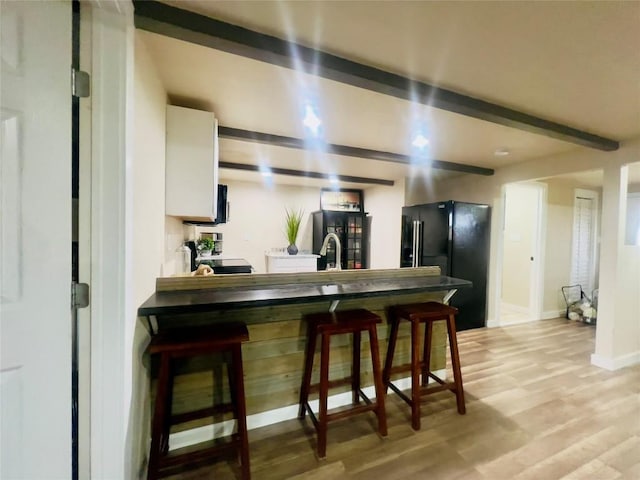 1342 Moose Trl, Kingsland, TX 78639 - kitchen featuring freestanding refrigerator, beamed ceiling, light wood-style flooring, a breakfast bar area, and baseboards