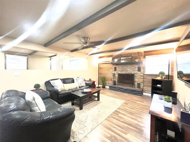 living room with ceiling fan, beam ceiling, a fireplace, and light hardwood / wood-style flooring