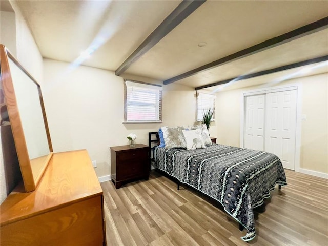 bedroom with beam ceiling, a closet, and light hardwood / wood-style floors