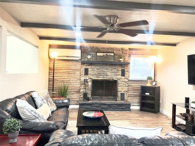 living room with hardwood / wood-style floors, beam ceiling, a stone fireplace, and an AC wall unit