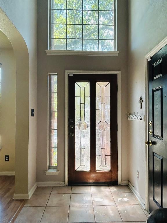 entrance foyer with a wealth of natural light, light tile patterned flooring, and a high ceiling