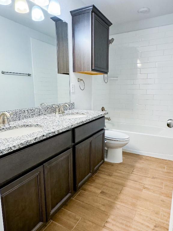 full bathroom with vanity, toilet, wood-type flooring, and tiled shower / bath