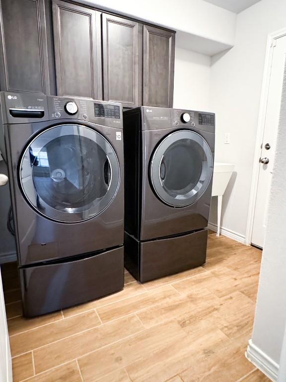 laundry area with cabinets, light hardwood / wood-style floors, and washer and clothes dryer