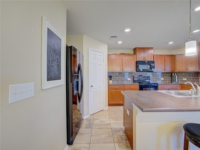 kitchen featuring sink, decorative light fixtures, a breakfast bar area, decorative backsplash, and black appliances