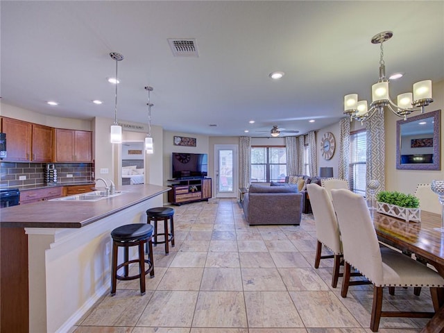 dining area featuring ceiling fan with notable chandelier and sink