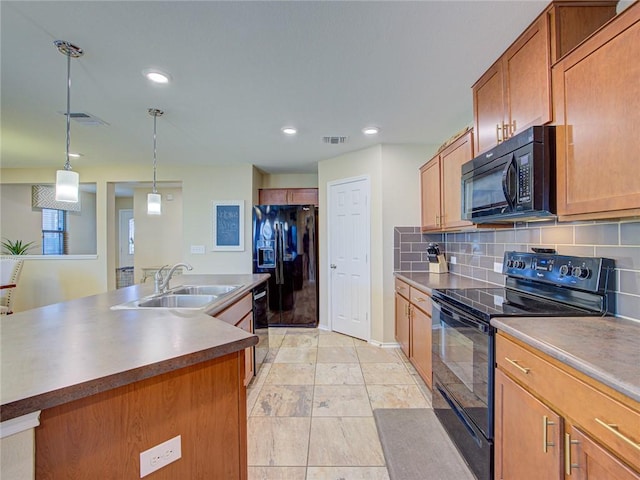 kitchen featuring decorative backsplash, sink, black appliances, a center island with sink, and hanging light fixtures