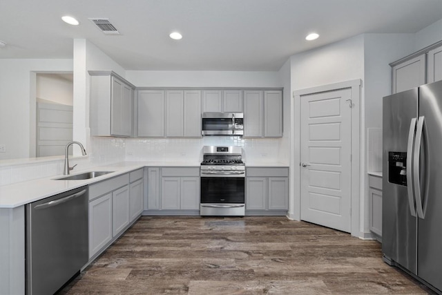 kitchen featuring gray cabinetry, sink, dark wood-type flooring, tasteful backsplash, and appliances with stainless steel finishes