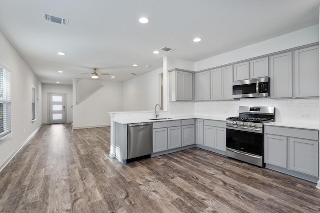 kitchen with stainless steel appliances, gray cabinets, ceiling fan, and dark wood-type flooring