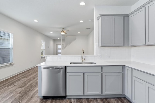 kitchen with gray cabinetry, sink, stainless steel dishwasher, dark hardwood / wood-style floors, and kitchen peninsula