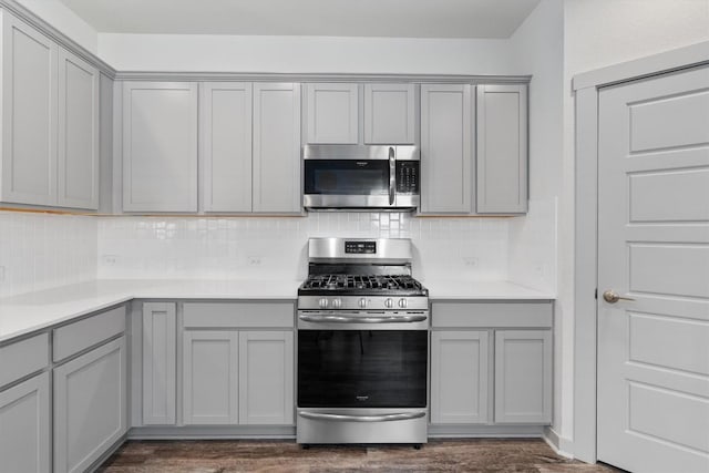 10400 Fulton Ave, Austin, TX 78754 - kitchen with stainless steel appliances, gray cabinetry, backsplash, and dark wood finished floors