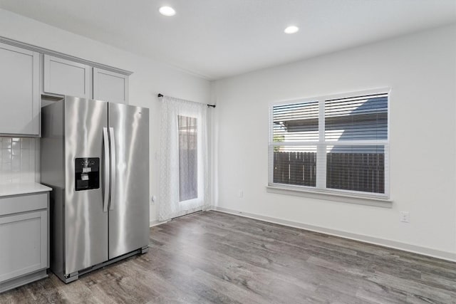 kitchen with stainless steel fridge with ice dispenser, hardwood / wood-style flooring, tasteful backsplash, and gray cabinetry