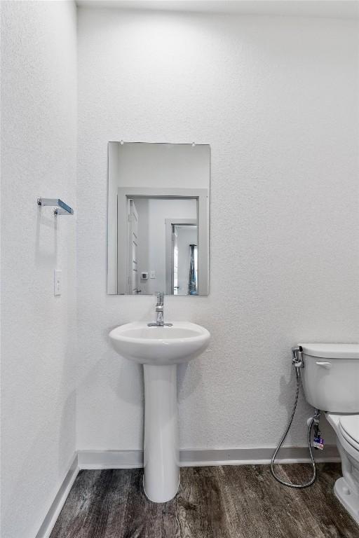 10400 Fulton Ave, Austin, TX 78754 - half bath featuring toilet, baseboards, and wood finished floors