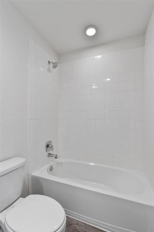 bathroom with toilet and tiled shower / bath