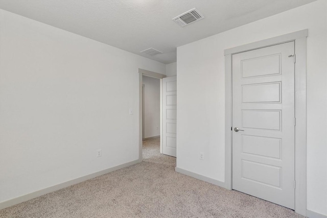 unfurnished bedroom with a textured ceiling and light colored carpet